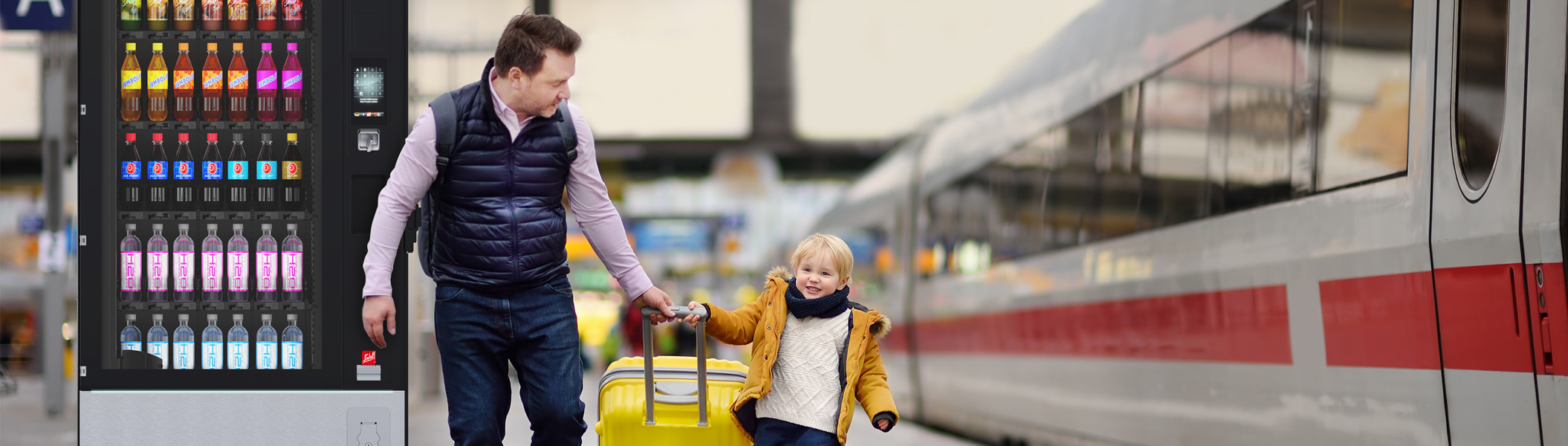 Ein Mann mit Kind am Bahnhof neben einem Automaten