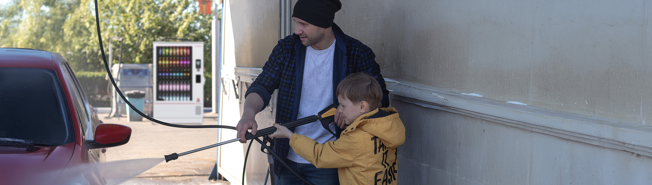 Ein Automat hinter einem Mann und einem Kind auf einer Autowaschanlage