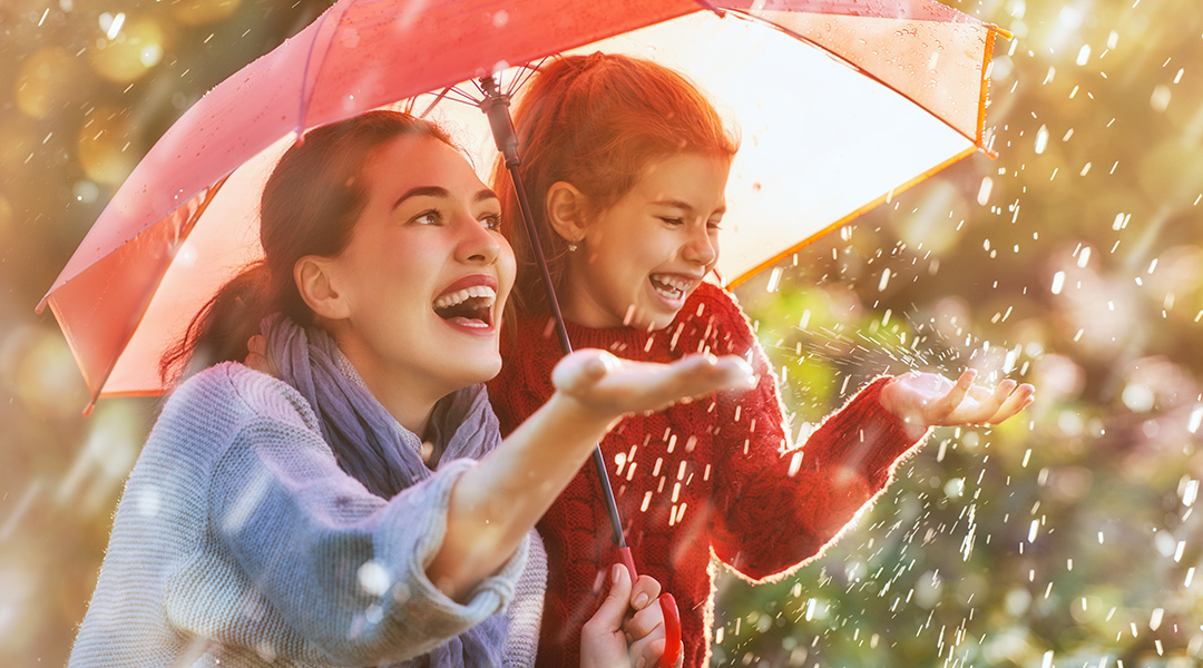 Eine Frau und ein Kind im Regen unter einem Regenschirm 