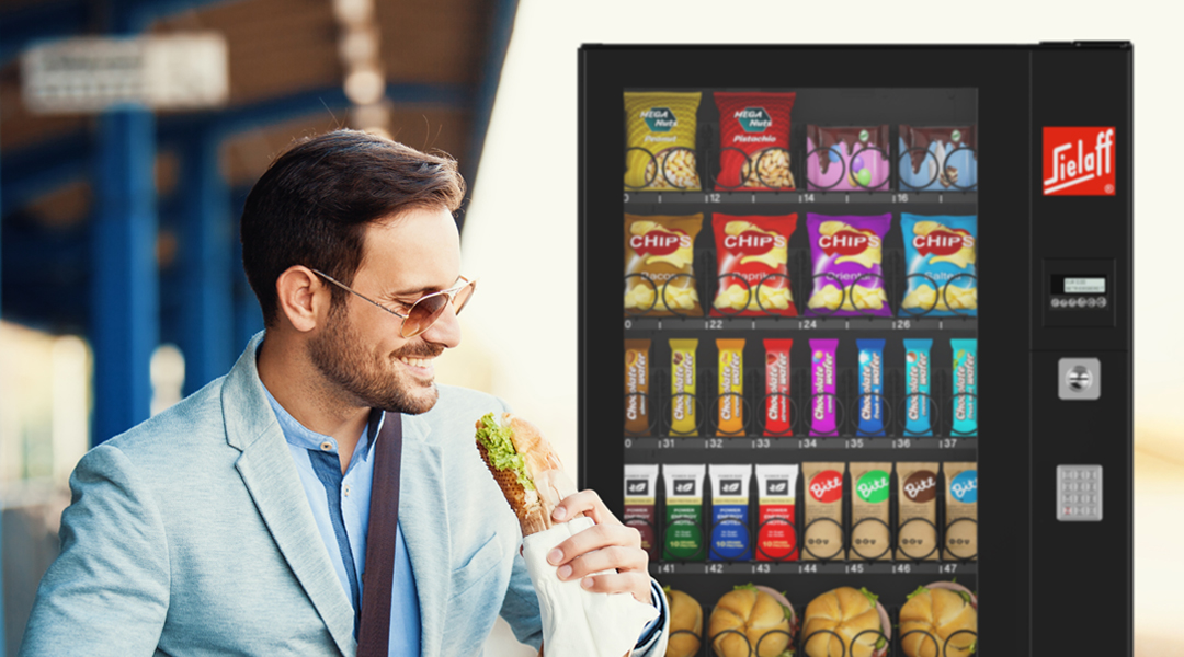 Ein essender Mann vor einem Automaten