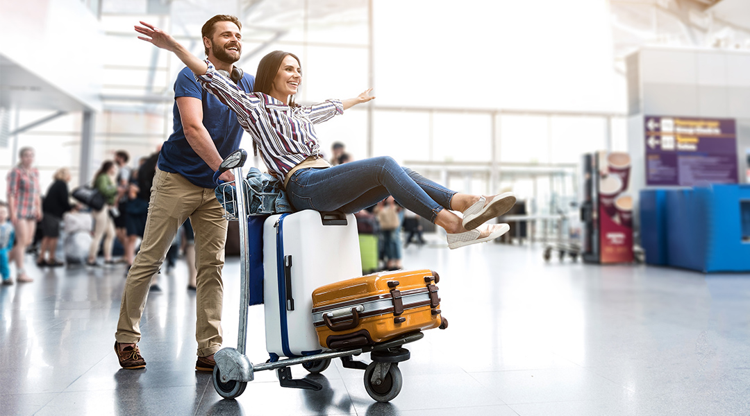 Zwei Glückliche Menschen mit Koffern auf einem Wagen