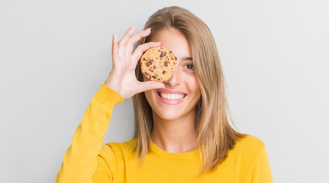 Eine Frau die einen Keks vor ihr Gesicht hält
