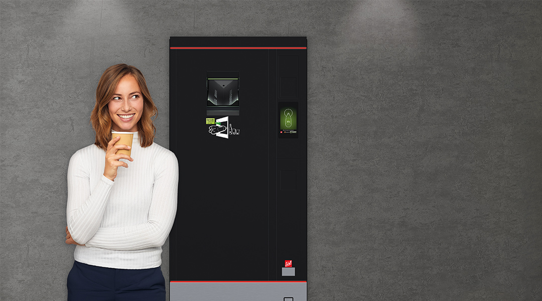 Eine Frau mit einem Kaffeebecher vor einem Automaten