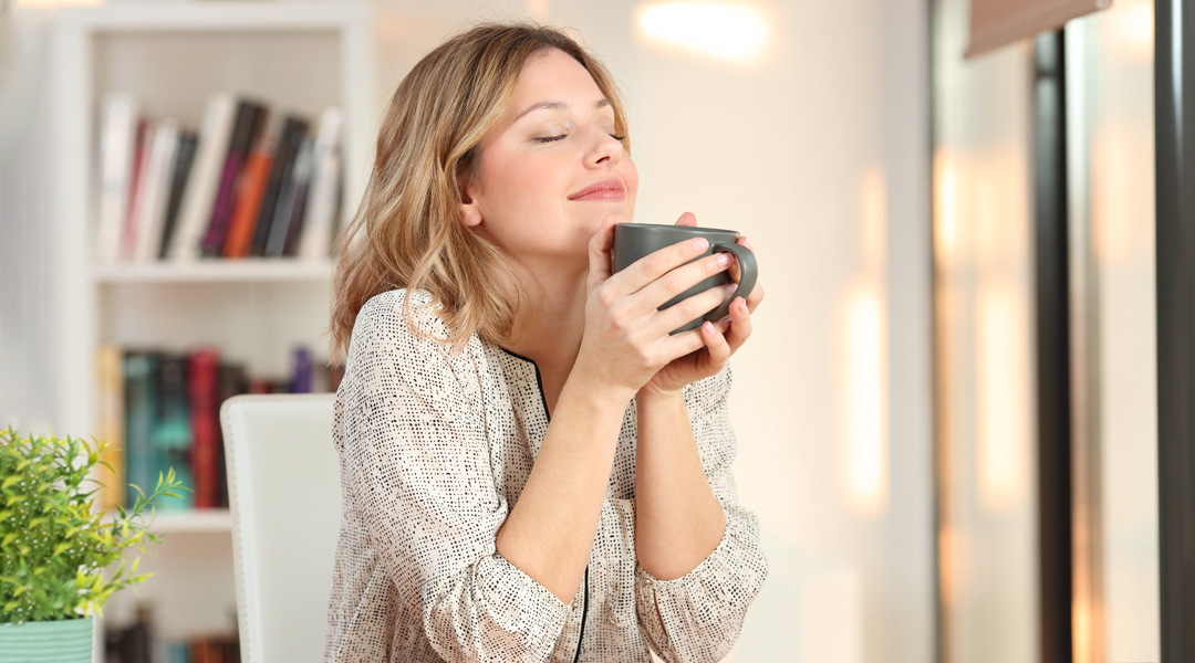 Eine Frau mit einer Kaffeetasse in beiden Händen